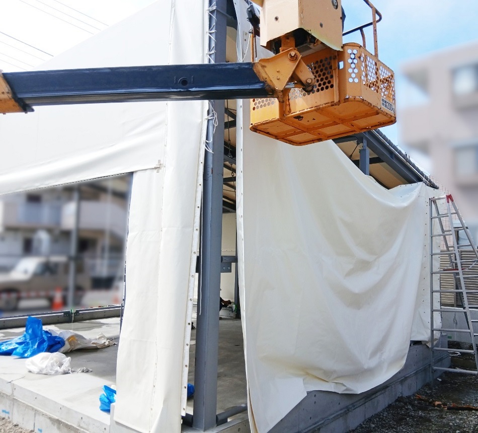 高所作業車を使用して慎重にシート取り付け
